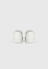 Baskets blanches en cuir lisse, avec un bout arrondi, un design bas, un collier rembourré et une semelle en caoutchouc. Lignes épurées avec des accents perforés.