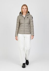 Hellgraue Steppjacke mit durchgehendem Reißverschluss, Kapuze und zwei Seitentaschen. Darunter wird ein weißes Oberteil getragen, kombiniert mit weißen Cargo-Hosen.