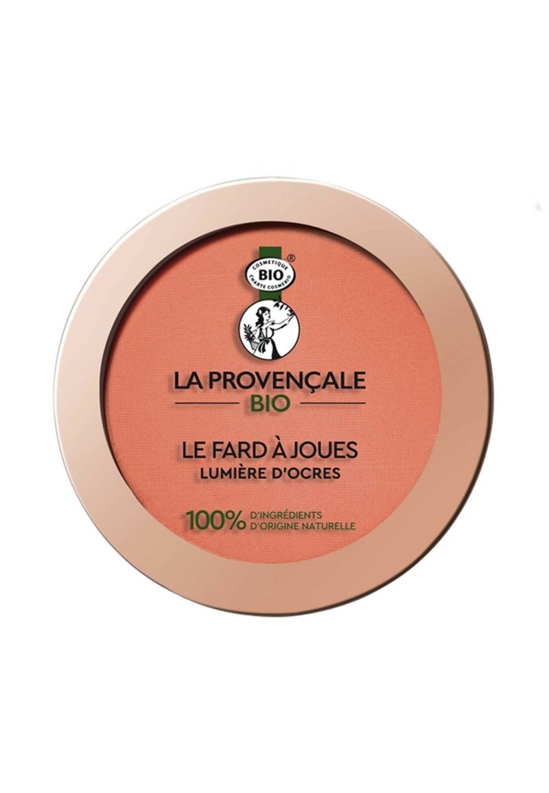 Poudrier de blush de forme ronde, présentant une teinte corail et une texture lisse. Le couvercle est bordé d'or et affiche une étiquette de produit biologique.