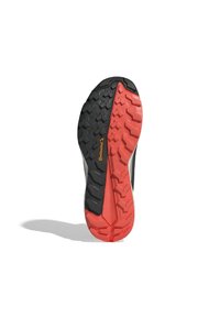Černá a červená atletická boty má podrážku s robustním vzorem, gumovou konstrukci a výrazné logo Continental na boku.