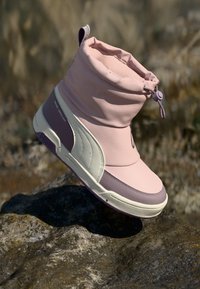 Roze en witte synthetische enkellaars met een zachte, geplooide bovenkant, ronde neus en gestructureerde zool; heeft een verstelbare trekkoordsluiting en subtiele kleuraccenten.