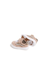 Zapatos de ante rosa claro con una correa de velcro, cordones blancos y suelas de goma blancas, con un logotipo marrón y blanco en la suela.