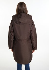 Brun polstret frakke med hætte, der har en indsnævret talje og lange ærmer. Stoffet har en glat overflade og en mellemlang skæring.
