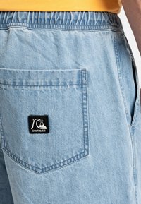 Lichtblauwe denimshorts met een elastische tailleband en een patchzak aan de rechter achterkant, versierd met een zwart Quiksilver-logo.