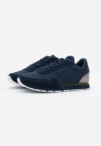 Dyp blå joggesko laget av syntetisk materiale med semsket skinn-aksenter, med en teksturert hæl, et mønstret yttersåle og et klassisk snølås-design.