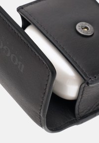 Étui en cuir noir avec une finition texturée, légèrement ouvert pour révéler un objet blanc à l'intérieur. Détail de bouton-pression circulaire en métal visible.