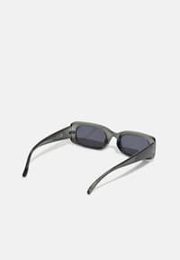 Gafas de sol rectangulares con un marco gris translúcido y lentes oscuros. Las patillas son alargadas y tienen un acabado brillante.