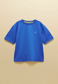 T-shirt bleu à manches courtes et col rond avec petit logo de lapin jaune brodé sur la poitrine gauche, présenté sur un fond beige.