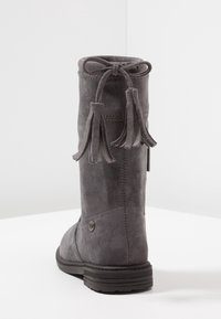 Bottines grises en daim mi-hauteur avec des franges décoratives nouées en nœud à l'arrière et une semelle en caoutchouc noir texturé.