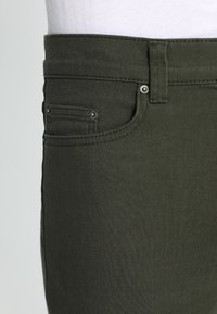 Olijfgroene denim broek met een klassieke vijf-pocketontwerp, stevige stiksels en metalen klinknagels op de voorzakken.