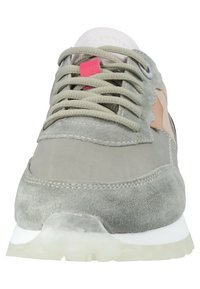 Sneaker in suede grigio con una punta liscia grigia, dettagli rosa chiaro e lacci grigi. La suola è bianca traslucida con una parte inferiore testurizzata.