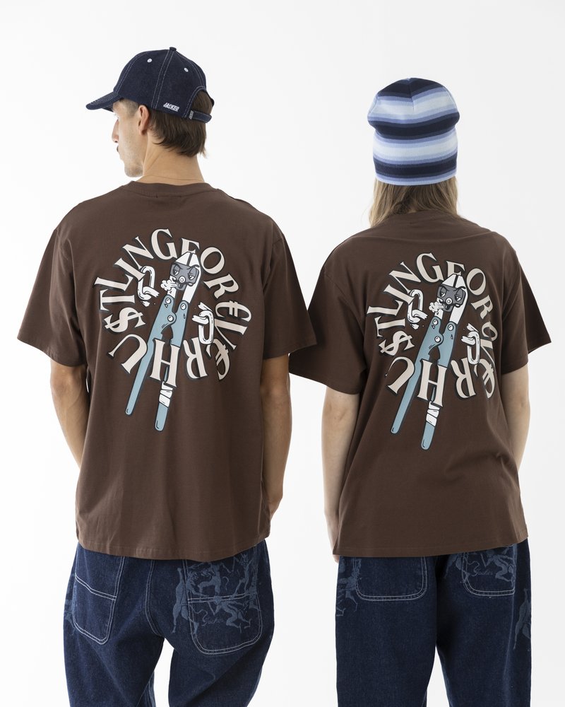 Brown cotton t-shirts with a graphic print featuring scissors on the back. Paired with blue denim jeans. Flatcaps and beanie worn.