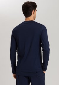 Camisa de manga larga de color navy hecha de una tela suave, con cuello redondo y un corte relajado, que presenta una textura lisa y sin patrones visibles.