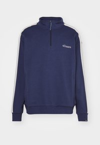 Sweatshirt bleu marine avec un col montant, fermeture éclair et rayures latérales contrastantes en gris clair. Doté d'un logo brodé sur la poitrine et de poignets côtelés.