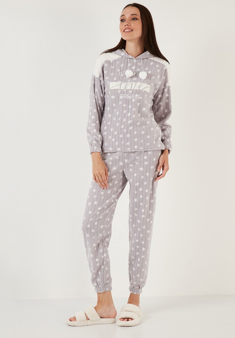 Šedý, měkký fleecový loungewear set s pruhovaným vzorem a bílými tečkami, kapucí a pom-pom detaily. Obsahuje pohodlné sladěné kalhoty.