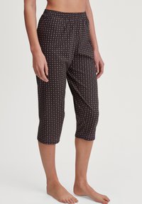 Zwarte, gestreepte capri-broek met een elastische tailleband. Bevat een geometrisch ontwerp in tinten paars en blauw op een donkere achtergrond.