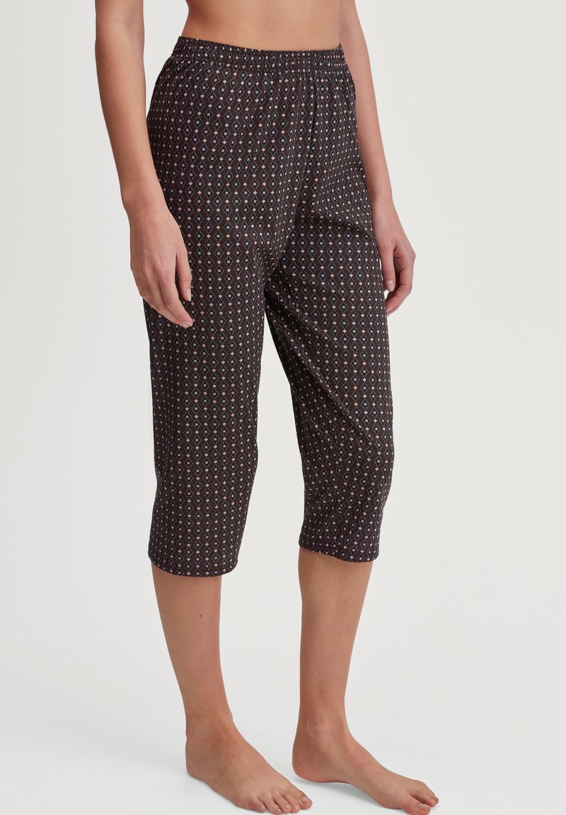 Zwarte, gestreepte capri-broek met een elastische tailleband. Bevat een geometrisch ontwerp in tinten paars en blauw op een donkere achtergrond.