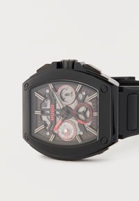 Μαύρο ρολόι χειρός Hugo με ορθογώνιο καντράν που δείχνει ημέρα, ημερομηνία και υποκαντράν 24 ωρών, με κόκκινες πινελιές και μαύρο λουράκι.