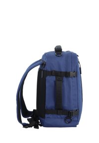 Mochila de tela azul con un diseño estructurado, cuenta con tirantes ajustables, bolsillo lateral de malla y acentos de hebilla. Textura suave, forma rectangular.