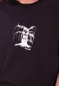 Svart T-shirt med en vit grafisk design av ett träd med stiliserade grenar och rötter, med varumärket "VOLCOM" i små bokstäver längst ner.
