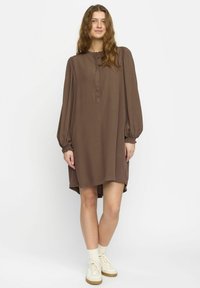 Rochie maro, cu mânecă lungă, guler înalt și butoni, având mâneci bufante și un tiv curbat. Material moale, ușor.