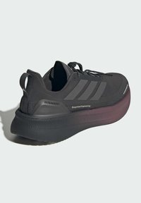 Černá běžecká bota s texturovaným svrškem, třemi matnými pruhy na boku a silnou, zužující se podrážkou. Má systém rychlého šněrování a poutko na nazouvání.