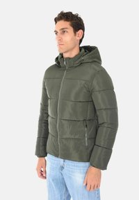 Giacca a vento verde olivastro con cappuccio, chiusura a zip frontale e tasche laterali. Presenta una texture liscia e lucida e un design a quadri orizzontali.