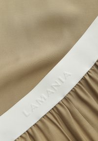 Ruda medžiaga su lygiu paviršiumi. Viršuje yra balta juosta su reljefine užrašu "LAMANIA", o apačioje - susiraukšlėtos plišės.