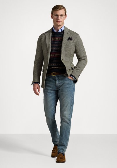 Gray herringbone blazer over a patterned sweater, light blue shirt, and light denim jeans. Brown loafers complete the look.