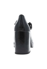 Chaussure à talon haut noire avec une finition brillante, un talon solide en bloc, un bout pointu et une sangle à boucle ajustable sur le côté.