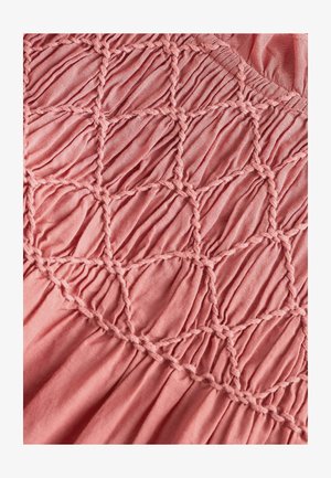 Tejido en tono rosa empolvado con textura fruncida, que presenta un detalle de smocking en forma de diamante hecho de hilos trenzados y material suave y ligero.