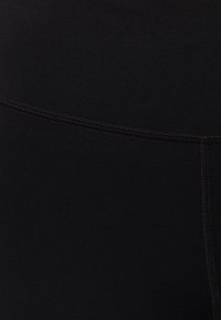 Leggings neri con una texture liscia e elasticizzata, dotati di cuciture piatte lungo la cintura per comfort e durata.