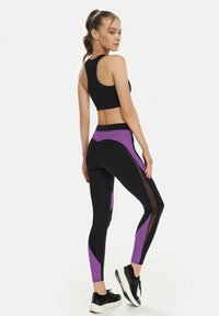Black athletic crop top with a racerback design, paired with black leggings featuring purple accents and mesh panels along the sides.