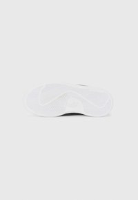 Semelle noire de sneaker avec une semelle extérieure en caoutchouc blanc texturé présentant un motif en chevron et un logo en relief au niveau du talon.