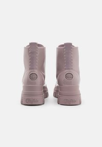 Botine roz deschis, realizate dintr-un material lucios, cu un tab de prindere texturat, detalii cu logo circular pe toc și talpi groase.