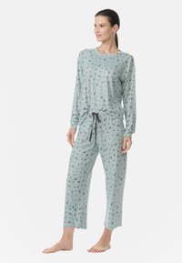 Vaaleansininen yöpuku, joka on valmistettu pehmeästä kankaasta. Settiin kuuluu pitkähihaisia paita ja löysät housut, joissa on nauhakuulokkeet, koristeltu kukkakuviolla.