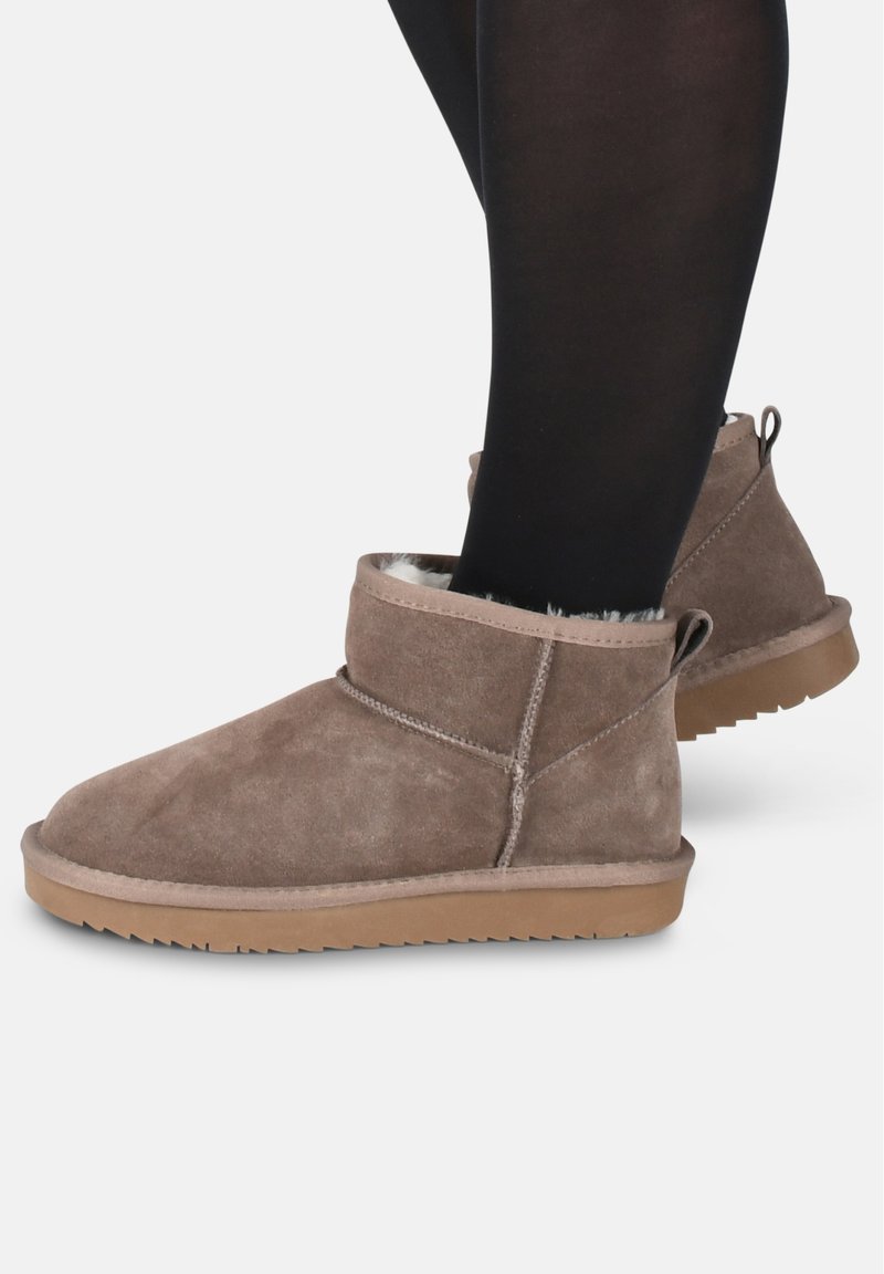 Botas de tobillo de ante marrón con un suave forro interior, puntera redondeada y suela de goma con un patrón de relieve.