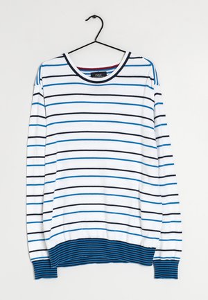 Pull blanc à manches longues avec des rayures horizontales bleues et noires, ourlet et poignets côtelés bleus, accroché à un cintre noir.