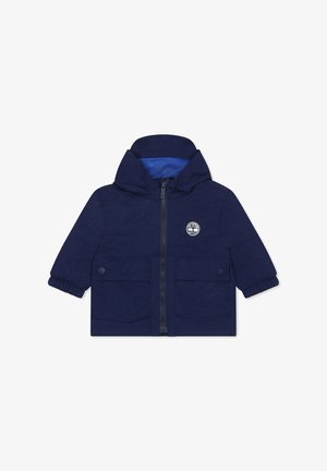 Marineblauwe kinderjas van lichtgewicht materiaal, met een rits aan de voorkant, een capuchon, twee voorzakken en een binnenvoering van gaas.