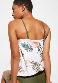 Top da bagno con stampa tropicale, realizzato in tessuto bianco, con spalline verdi regolabili e dettagli floreali in arancione e verde. Texture liscia, vestibilità comoda.