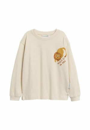 Beige shirt met lange mouwen met een speelse leeuwengrafiek en de tekst "Magic is in you" aan de voorkant rechts.