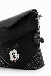 Fekete műbőr táska Mickey Mouse applikációval, szegecselt díszítésekkel és levehető charm-mal. Záródik egy hajtogatott fedelet, texturált részletekkel.