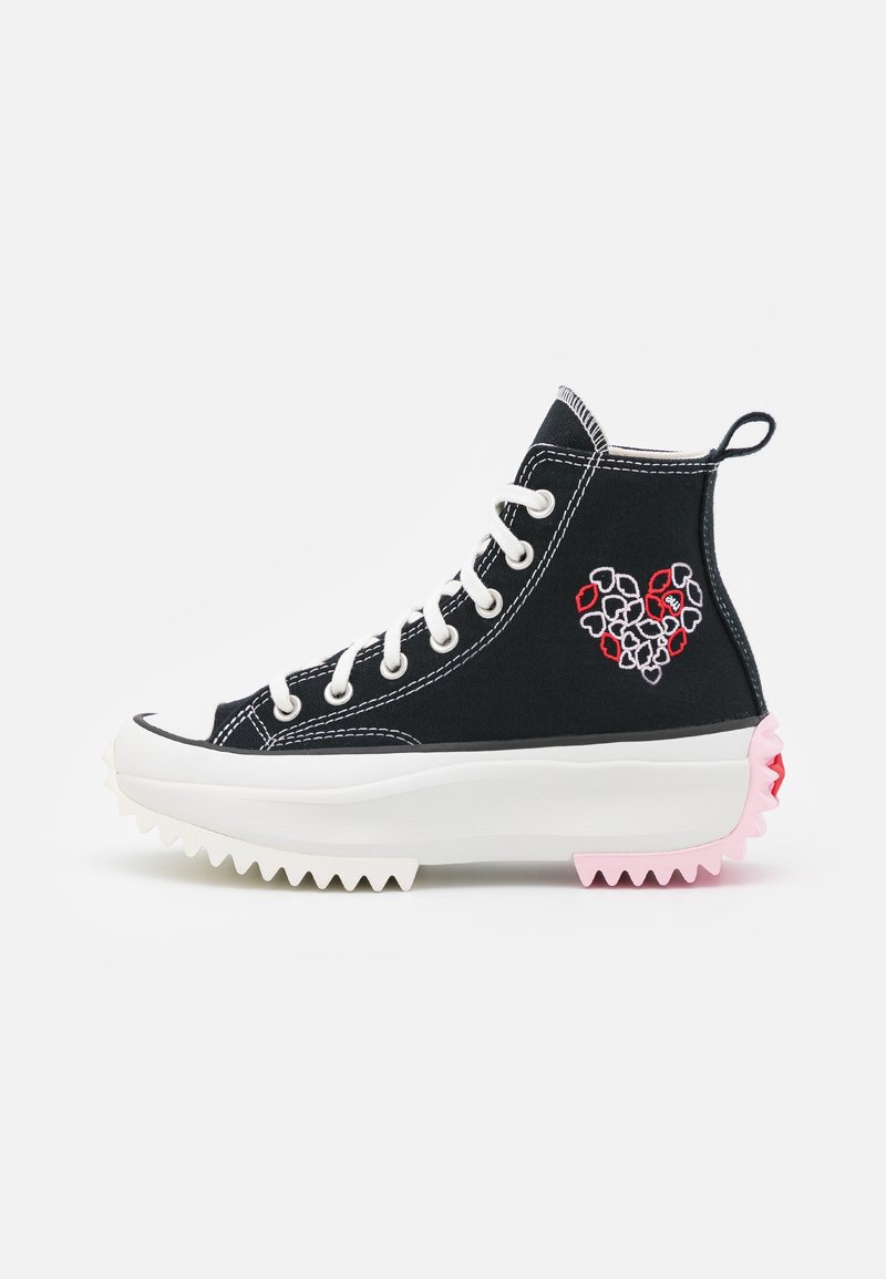 Baskets montantes noires avec des lacets blancs, des coutures contrastantes et un motif brodé en forme de cœur en rouge et gris. Semelle épaisse blanche et rose.