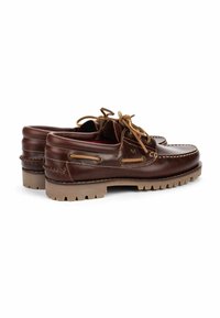 Zapatos de barco de cuero marrón con una parte superior lisa, cordones beige en contraste, costuras blancas y una suela de goma texturizada para mayor agarre.