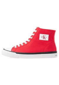 Červené vysoké tenisky vyrobené z plátna s bílým gumovým špičkou, černým akcentem na podrážce a logem značky "Calvin Klein Jeans."