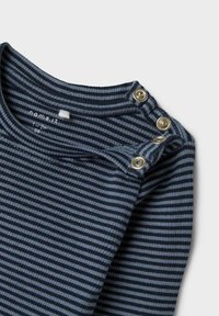 Pružasta majica s dolgimi rokavi v temno modri in svetlo modri bombažni tkanini, z okroglim izrezom in tremi pritisnimi gumbi na rami.