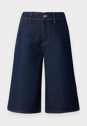 Denim culottes in dark blue with a loose fit. Features front pockets, a button closure, and contrasting yellow stitching along the seams.