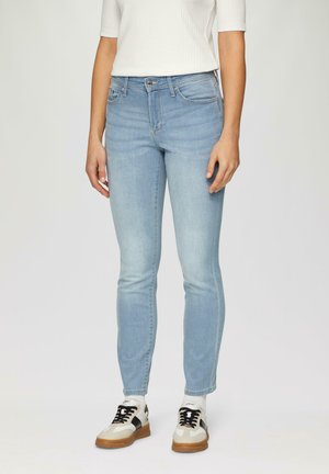 Lichtblauwe skinny jeans van denim. Heeft een middelhoge taille, voor- en achterzakken en subtiele vervaging. Gepaarde met zwart-witte sneakers.