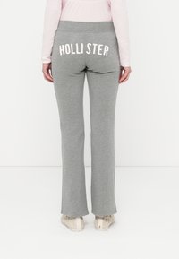 Γκρι φαρδιές φόρμες με μαλακή υφή και ελαστική μέση. Διαθέτουν λευκά γράμματα "HOLLISTER" στο πίσω μέρος.