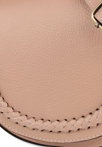 Leren tas in licht beige met getextureerde afwerking, voorzien van gevlochten detail langs de rand en messing sluiting.